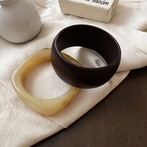 Close-up of brown resin and amber translucent bangles on elegant silk fabric