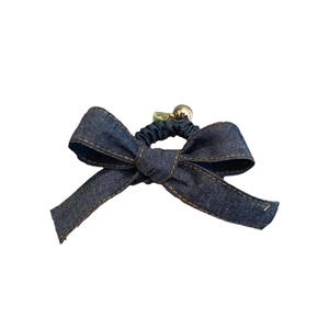 Chouchou en denim bleu avec nœud papillon, perle dorée et breloque cœur sur fond blanc