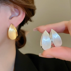 Dettaglio di orecchini a goccia in oro 18k e argento con finitura opaca su modella