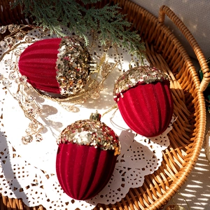 Detail of red flocked acorn Christmas ornaments with golden sequins in a cozy tray