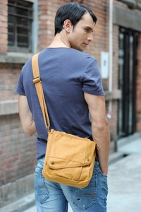 Close-up of yellow canvas messenger bag with adjustable strap and metal snap closure
