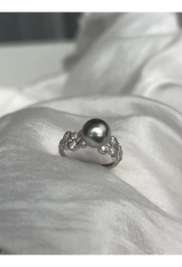 Detailed view of a silver ring featuring a grey pearl and zircon on white silk