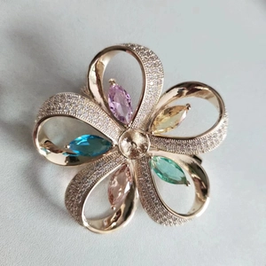Détail macro d'une broche fleur en or rose sertie de zircons colorés de taille marquise