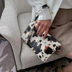 Fashionable cow print envelope clutch bag with wristlet and decorative tassel charm