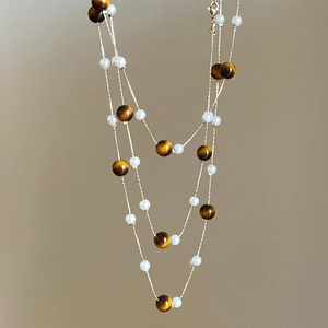 Collier vintage à trois rangs avec pierres œil de tigre et perles sur fond marron chaud