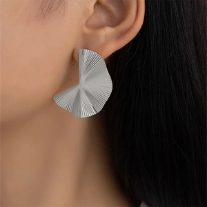 Modern silver pleated fan earrings with irregular wave design worn by female model