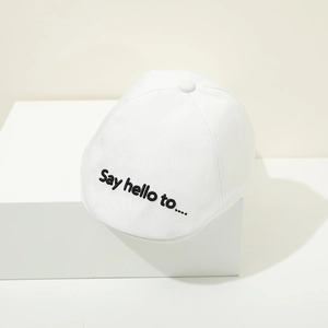 Detail of white cotton baby beret featuring black Say Hello embroidery and top button