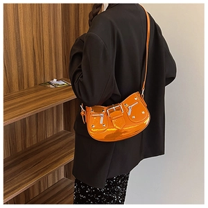 Close-up of glossy orange patent leather shoulder bag with silver studs and hardware details