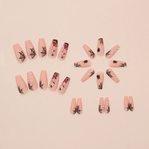 Macro detail of Halloween press-on nails with spider web, pumpkin designs and rhinestones