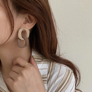 Detailed view of bicolor acrylic geometric drop earrings worn by a model in soft lighting