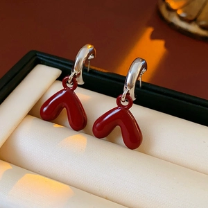 Macro shot of elegant red heart resin earrings with silver C-shaped hooks on jewelry box