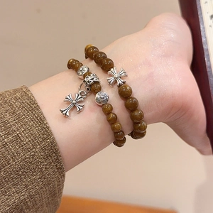 Détail de bracelets perlés avec pierres oeil de tigre brunes et breloques de croix en argent