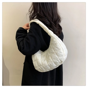 Detail of white quilted nylon cloud bag shown on shoulder with minimalist winter style