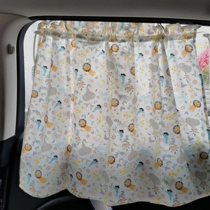 Detail of baby car sunshade featuring cartoon lion and goose patterns on fabric