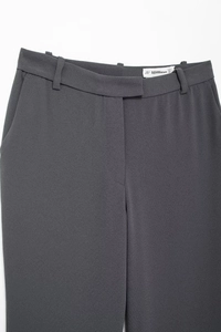 Detailed view of dark grey suit trousers waistline featuring belt loops and smooth fabric