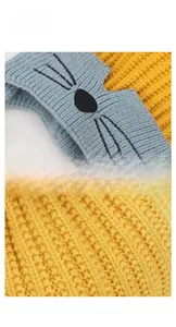 Detailed close-up of knit texture and cat embroidery on yellow and blue kids hat