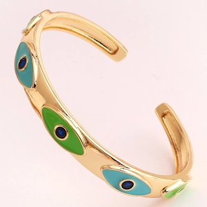 Detail of gold evil eye cuff bracelet with blue and green enamel and small gemstones