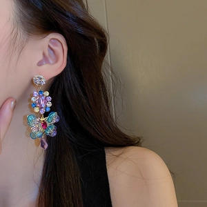 Detailed close-up of asymmetrical vintage crystal butterfly earrings on a model's ear
