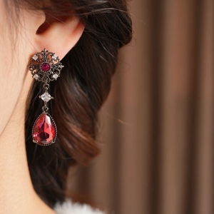 Détail de boucles d'oreilles vintage fleur ajourée avec goutte de zircon rouge et argent