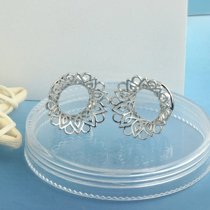 Pair of hollow silver steel ear gauges with mandala flower design in macro view