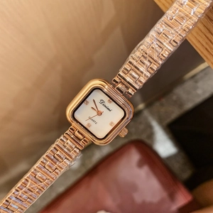 Close-up of golden square watch with shell dial, crystal markers and protective film