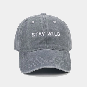 Close-up of white STAY WILD embroidery on grey washed cotton vintage baseball cap