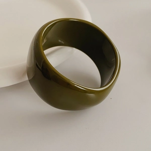 Macro view of wide resin bangle in olive green with high polished finish and smooth edges
