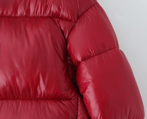 Detail of red glossy padded jacket showing quilted texture and shiny polyester fabric