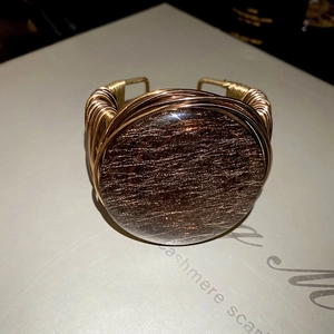 Detailed macro of handmade gold wire-wrapped bangle with round dark brown crystal stone
