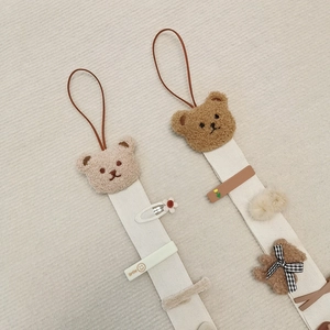 Detail of plush bear hair accessory organizer with white canvas straps and smile clips