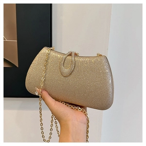 Detail of gold glitter clutch bag with rhinestone oval ring clasp and chain strap