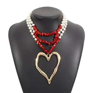 Detail of layered pearl and red turquoise necklace with a large gold heart pendant
