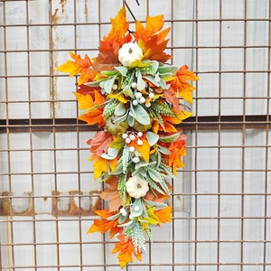 Close-up of autumn door swag with maple leaves and small white pumpkins on a metal grid