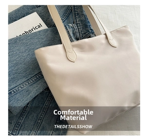 Detail of minimalist beige nylon tote bag with smooth texture on blue denim background