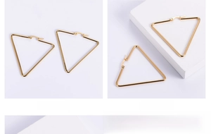 Macro shot of minimalist gold triangular hoop earrings made of polished stainless steel