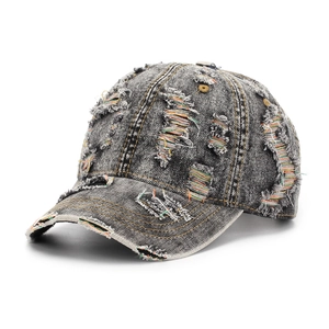 Close-up of distressed denim baseball cap featuring colorful thread details and torn holes