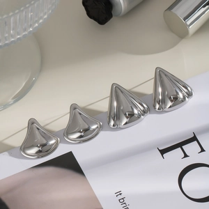 Detailed view of four polished silver fan-shaped stud earrings arranged on a magazine