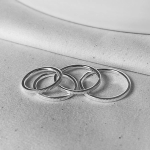 Close-up of four stacked S925 sterling silver rings with vertical textured patterns