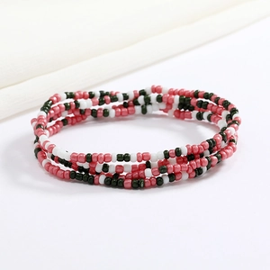Macro detail of layered red, white and dark green glass seed bead body chain on fabric