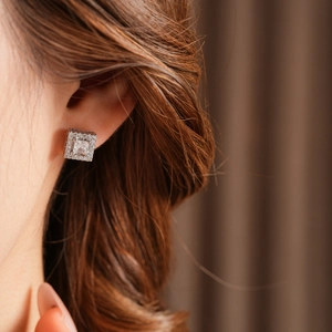 Close-up of sparkling square zircon stud earrings with silver plating on model's ear