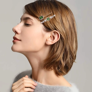 Close-up of elegant emerald green crystal and faux pearl hair pins on model's hair