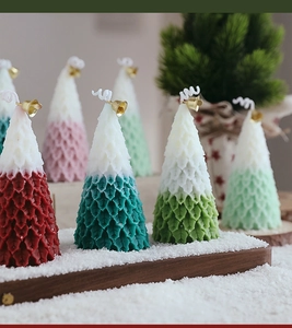 Macro view of Christmas tree candles with bell details on snowy wooden tray