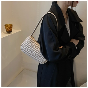 Detail shot of beige shoulder bag with unique wavy quilted texture and soft leather finish