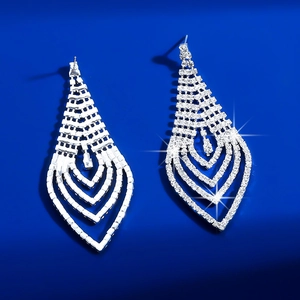 Macro shot of silver V-shaped fringe earrings with rhinestones on a blue backdrop