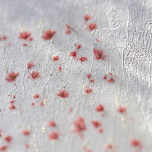 Macro shot of pink floral nail stickers with gold glitter accents on textured background