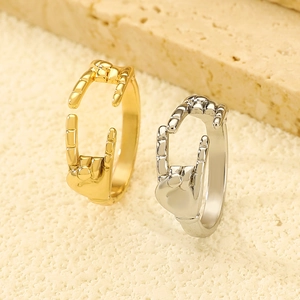 Detailed close-up of gold and silver rock gesture rings on a textured stone surface