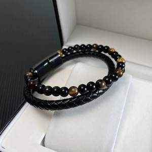 Close-up of double-layer men's bracelet with red tiger eye beads and braided leather