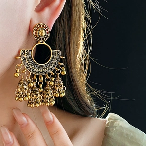 Detailed view of vintage gold Jhumka style earrings with fan patterns and bell tassels