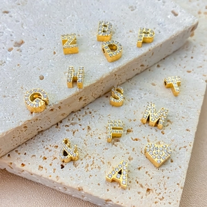 Macro shot of gold-plated alphabet charms with micro-pave cubic zirconia on stone base