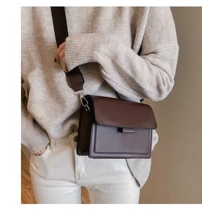 Detail of dark brown leather crossbody bag with wide shoulder strap worn by a model